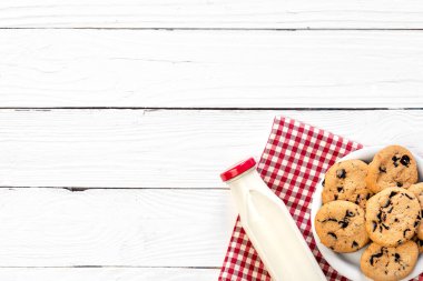 Bottle of milk and cookies on a wooden background, top view, rustic style, copy space.