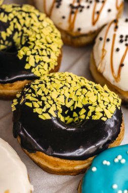 Delicious donuts of different flavors on paper close up, assorted colorful donuts.