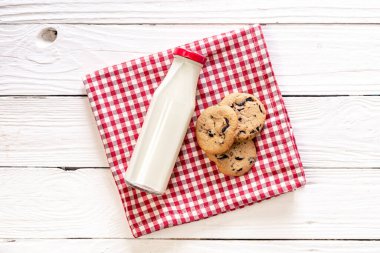 Bottle of milk and cookies on a wooden background, top view, rustic style.