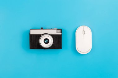 Vintage camera and computer mouse on a blue background isolated, flat lay.