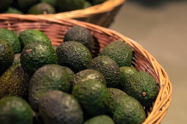 Avocados in basket for sale at fruit stall, close up.