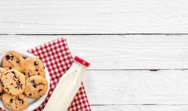 Bottle of milk and cookies on a wooden background, top view, rustic style, copy space.