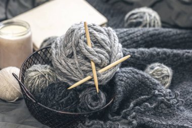 Composition with gray threads for knitting and candles, close-up of yarn with flowers.