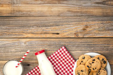 Milk and cookies with chocolate on a wooden background, flat lay, copy space.
