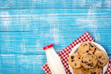 Bottle of milk and cookies on a wooden background, top view, rustic style, copy space.