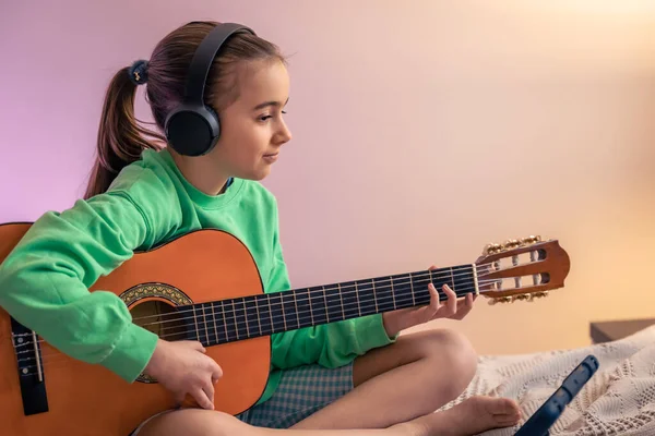 Little girl learns to play the guitar, music lesson with online teacher, distance learning to play the guitar, copy space.