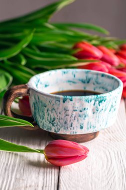 Spring composition with a cup of coffee and tulips on a wooden background.