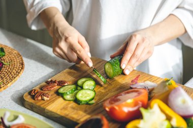 A woman cutting fresh vegetables for salad, healthy food and diet.