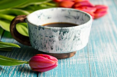 Spring composition with a cup of coffee and tulips on a wooden background.