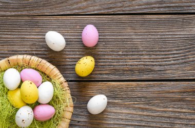 Easter eggs in a decorative nest on a wooden background, top view, copy space, rustic style.