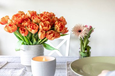 A bouquet of tulips and a candle on the table, the concept of serving and decor, a cozy home.