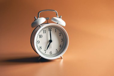 White alarm clock on brown background isolated, copy space.