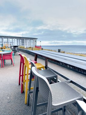 Multi-colored chairs and tables on the terrace of a cafe by the sea.