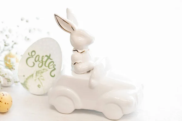 Easter background with a ceramic hare in the car and Easter eggs on a white background,