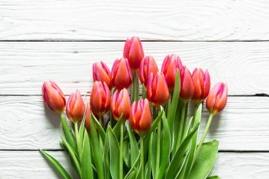 Bouquet of pink tulips on a white wooden background, top view, close up.