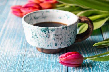 Spring composition with a cup of coffee and tulips on a wooden background.