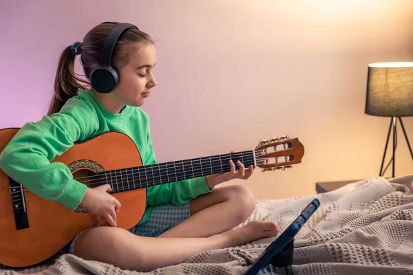 Little girl learns to play the guitar, music lesson with online teacher, distance learning to play the guitar.