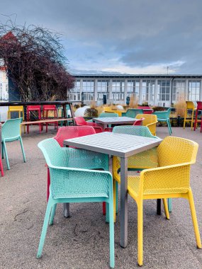 Multi-colored chairs and tables on the terrace of a cafe by the sea.