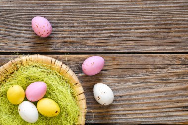 Easter eggs in a decorative nest on a wooden background, top view, copy space, rustic style.