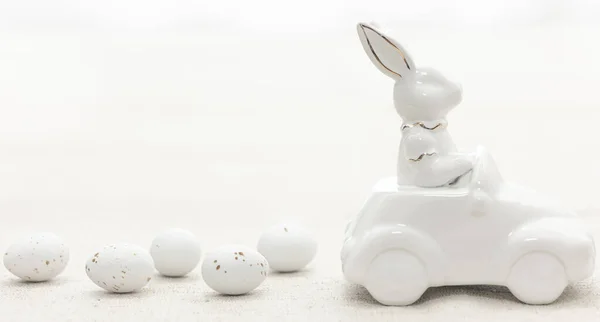 Decorative ceramic hare in a car and Easter eggs, close-up, Easter decor concept.