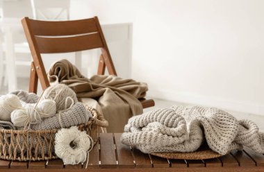 Odanın içindeki ahşap bir bankta örgü örmek için iplik dolu sepet. Örgü konsepti..