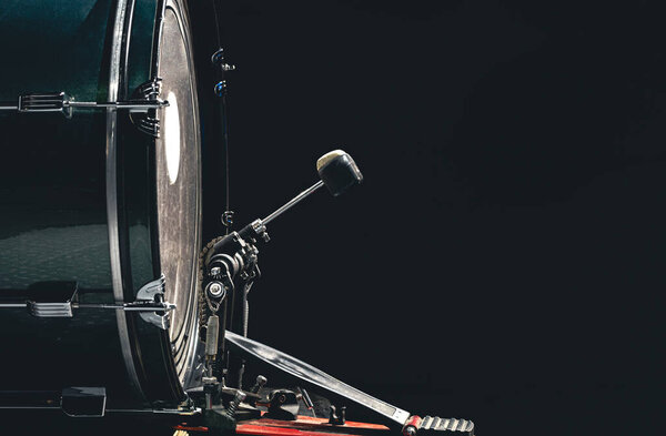 Bass drum with pedal, musical instrument on black background, copy space.