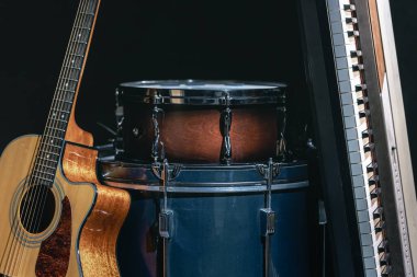 Siyah zemin üzerinde akustik gitar, davul ve anahtarlar, müzikal yaratıcılık kavramı..