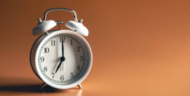 White alarm clock on brown background isolated, copy space.