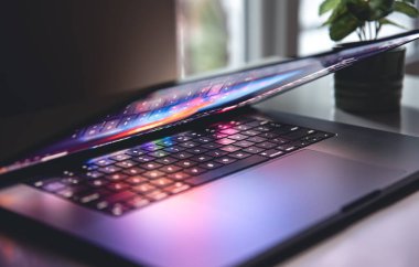 Geceleri çalışan bir dizüstü bilgisayarın klavyesini renkli bir şekilde kapat. Birden fazla renk arkaplanı olan bir ekran görüntüsünün aydınlatılmasıyla birlikte...