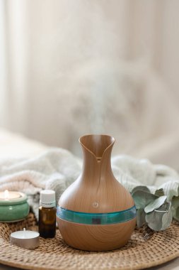 Bulanık arka planda aroma yağı yayıcı lambasıyla sıcacık spa kompozisyonu.