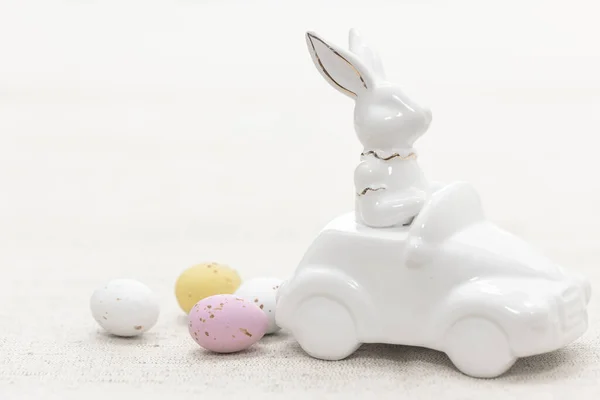 Decorative ceramic hare in a car and Easter eggs, close-up, Easter decor concept.