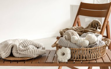 Odanın içindeki ahşap bir bankta örgü örmek için iplik dolu sepet. Örgü konsepti..