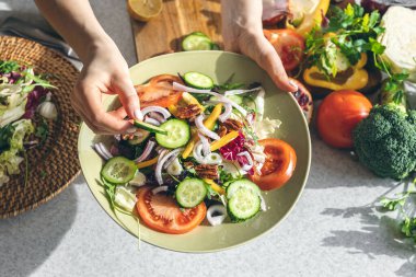 A woman making fresh vegetable salad, close-up, concept of diet and healthy eating.