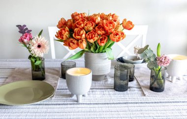 A bouquet of tulips, other flowers and a candle on the table, the concept of serving and decor, a cozy home.