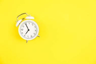 Sarı zemin üzerinde beyaz alarm saati, düz konum, kopyalama alanı.