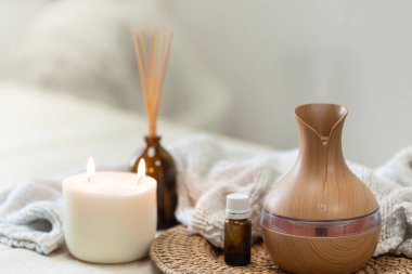 Bulanık arka planda aroma yağı yayıcı lambasıyla sıcacık spa kompozisyonu.