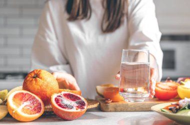 Close-up, a glass of water in female hands in the kitchen, the concept of maintaining water balance and health.