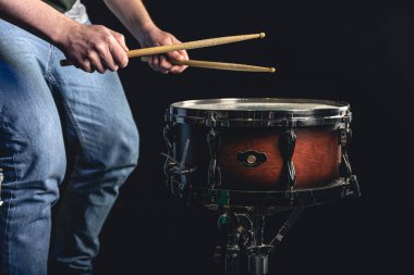 Bir erkek davulcu karanlık bir arka planda trampet çalar, bir müzik enstrümanı.