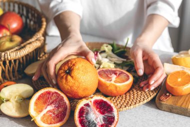 Oranges in female hands on the kitchen table, close-up, the concept of healthy eating and health.