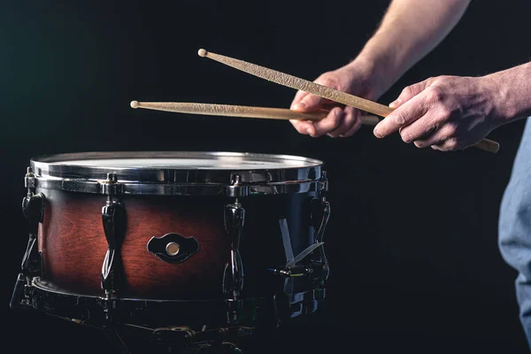 stock image A male drummer plays the snare drum on a dark background, a musical percussion instrumentman.
