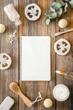 Tahta arka plan, hijyen ve banyo konseptine sahip defter ve vücut bakımı öğeleri içeren spa kompozisyonu.