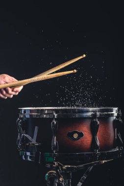 Bir erkek davulcu karanlık bir arka planda trampet çalar, bir müzik enstrümanı.