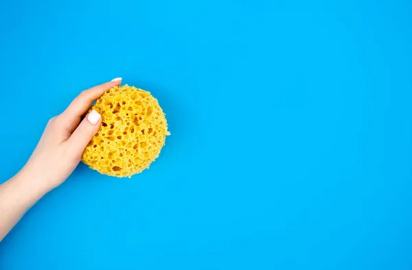 stock image Washcloth for a shower in female hands on a blue background, flat lay, copy space.