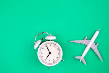 Çalar saat ve uçak modeli yeşil zemin, düz yatış, kopyalama alanı.