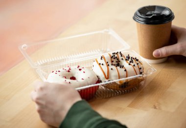 Plastik tepside iki iştah açıcı çörek ve erkek ellerinde kahve, yakın plan, lezzetli atıştırmalık, tatlı..