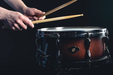 Davulcu davul çubuklarıyla davula vuruyor. Siyah arka planda su sıçratıyor..