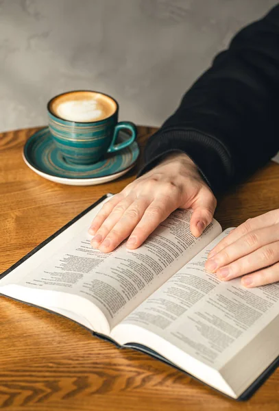 A cup of coffee and a Bible on the table, a Christian man is reading the Bible. morning, the concept of faith in God.