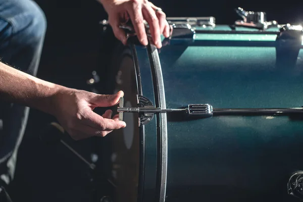 Bass drum and man, musical instrument on black background, close up.