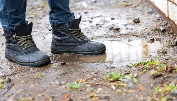 ジーンズとブーツを着た男が田舎の雨の日に沼を歩き足を閉じて — ストック写真