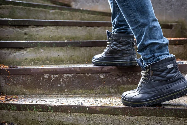 A man in wet boots on old steps, legs close-up.